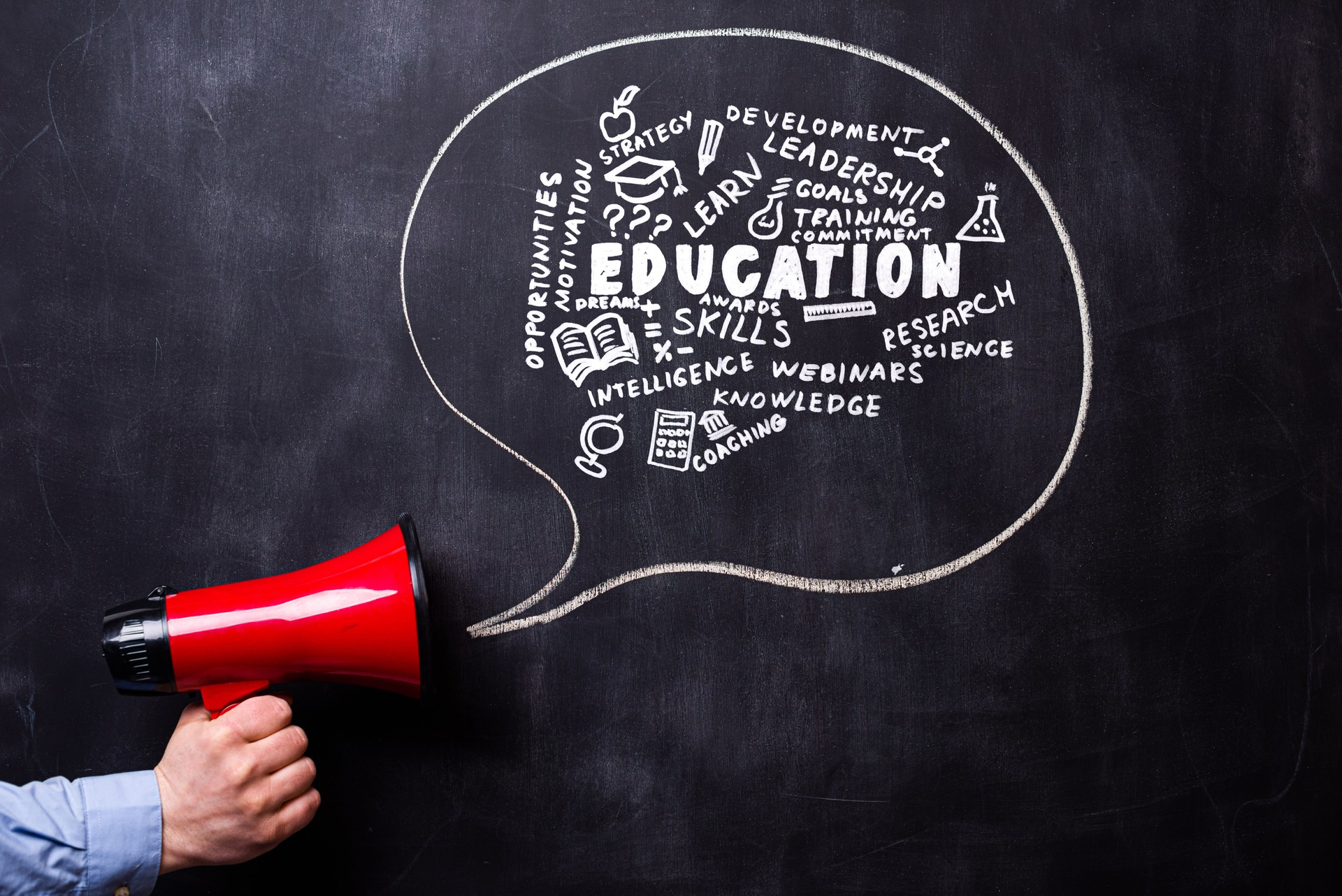 Man holding red loudspeaker in front of a blackboard. There is a hand drawn message bubble.